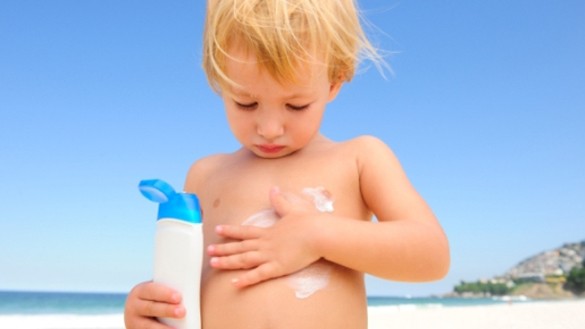 child putting on sunscreen